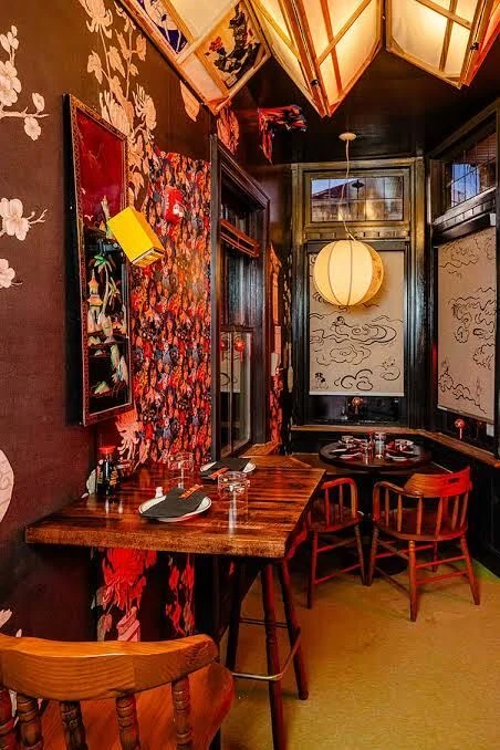 Bareo's corner dining tables under paper lanterns and painted wallpaper