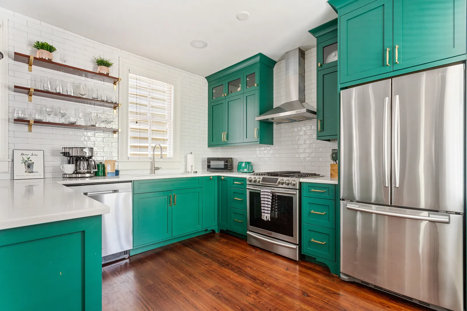 The julep green chef's kitchen with brass hardware and stainless appliances