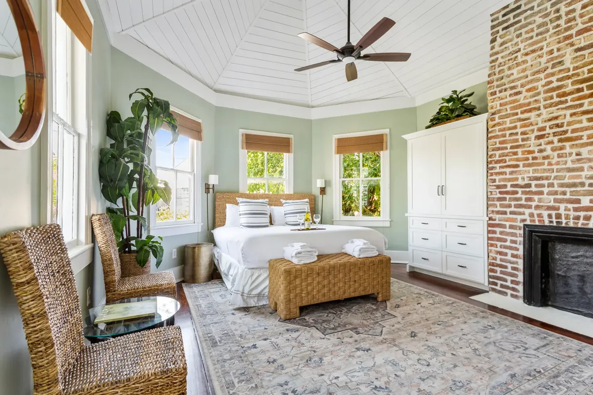 A primary king suite under the octagonal shiplap turret ceiling with original brick fireplace