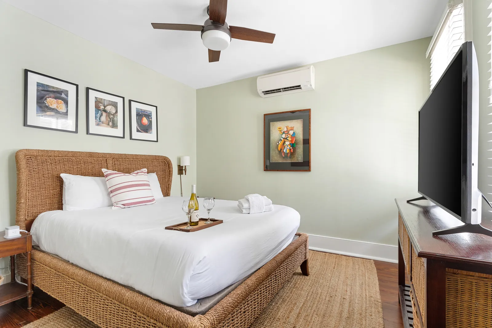 A king bedroom with a woven rattan bed and large TV
