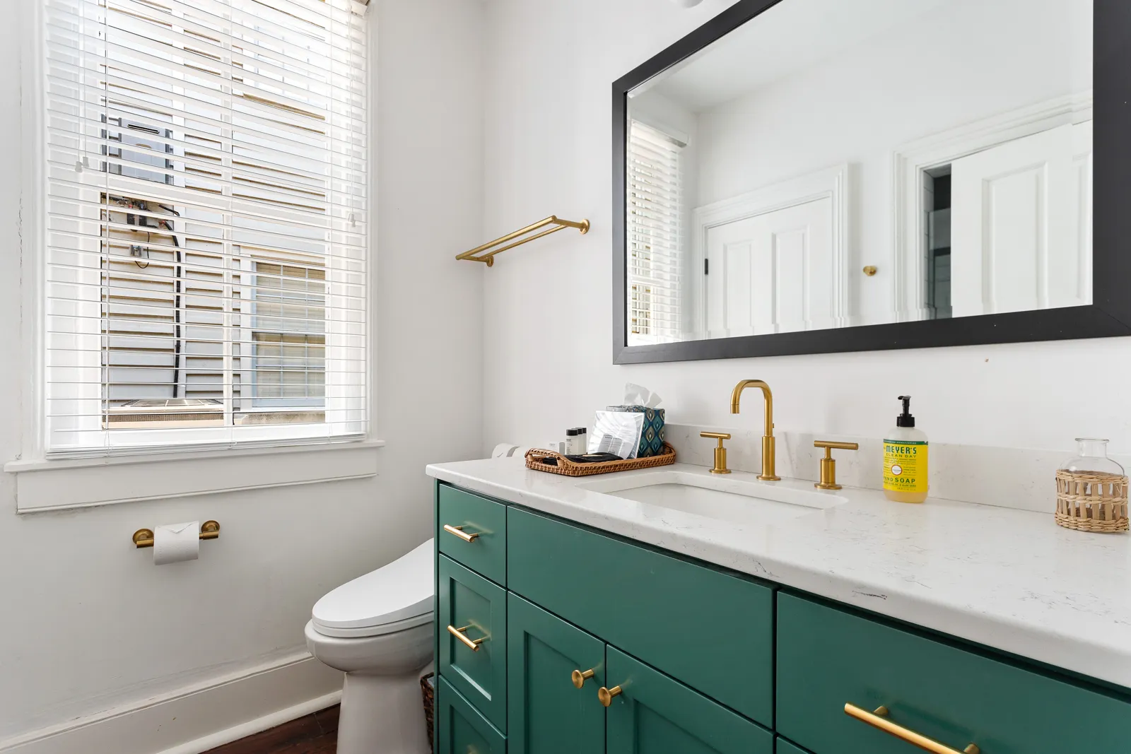 A full bathroom with a julep green vanity and brass fixtures