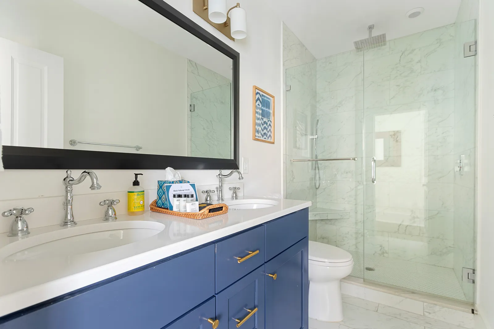 A double-sink bathroom in blue with a glass shower