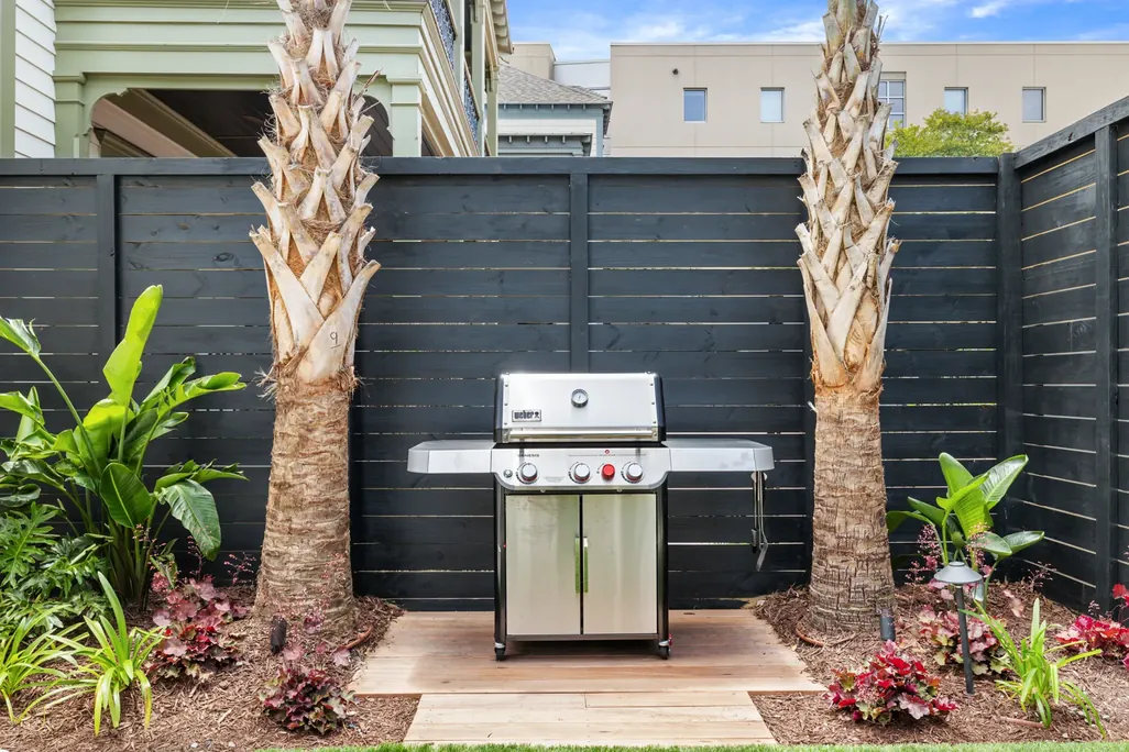 The gas grill beside the pool, framed by palms
