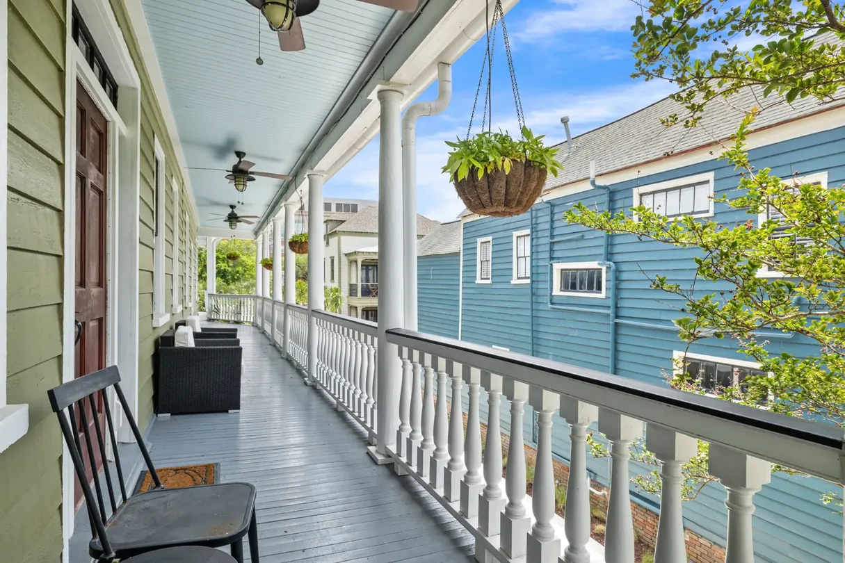The long second-floor porch of The Mint Julep Residence with hanging ferns