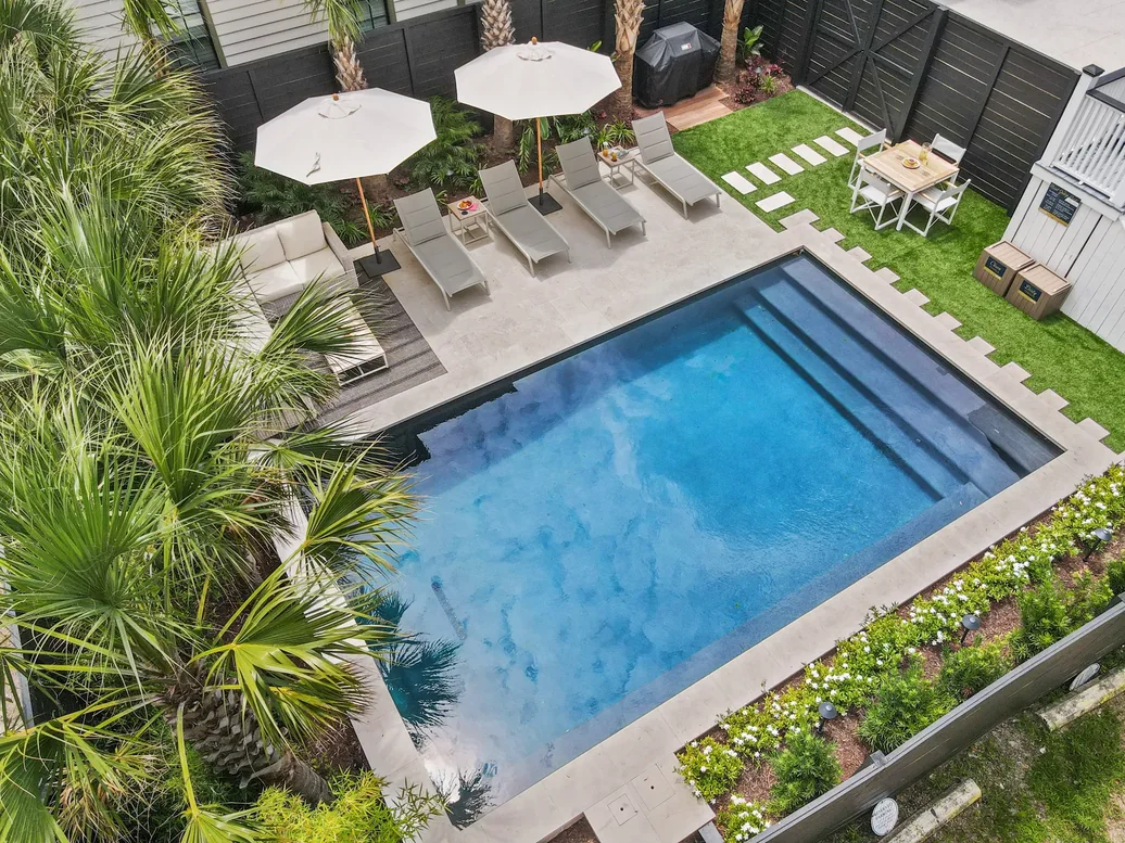 The pool and sun loungers from above with umbrellas and lawn