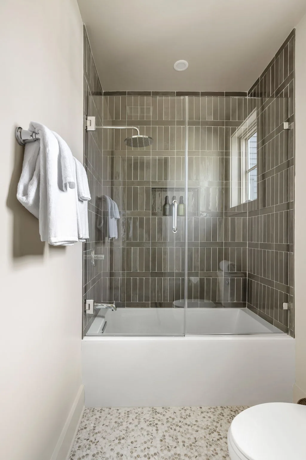 The sister residence's ensuite bath in deep olive tile with a pebble stone floor