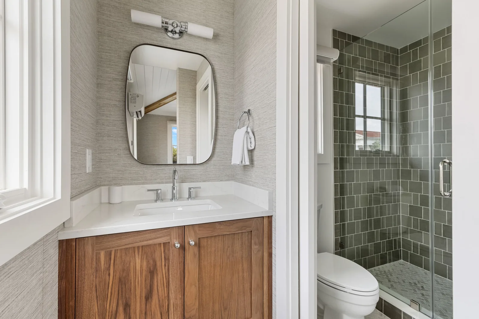 A king ensuite with a walnut vanity and the sage green walk-in shower beyond