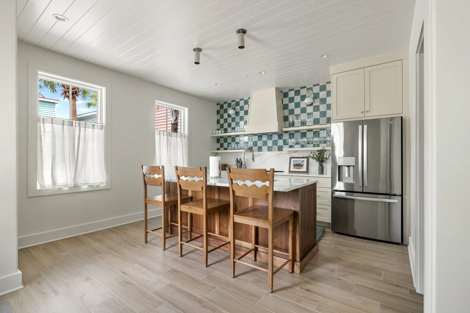 The chef's kitchen with green checkered tile and an island that seats three