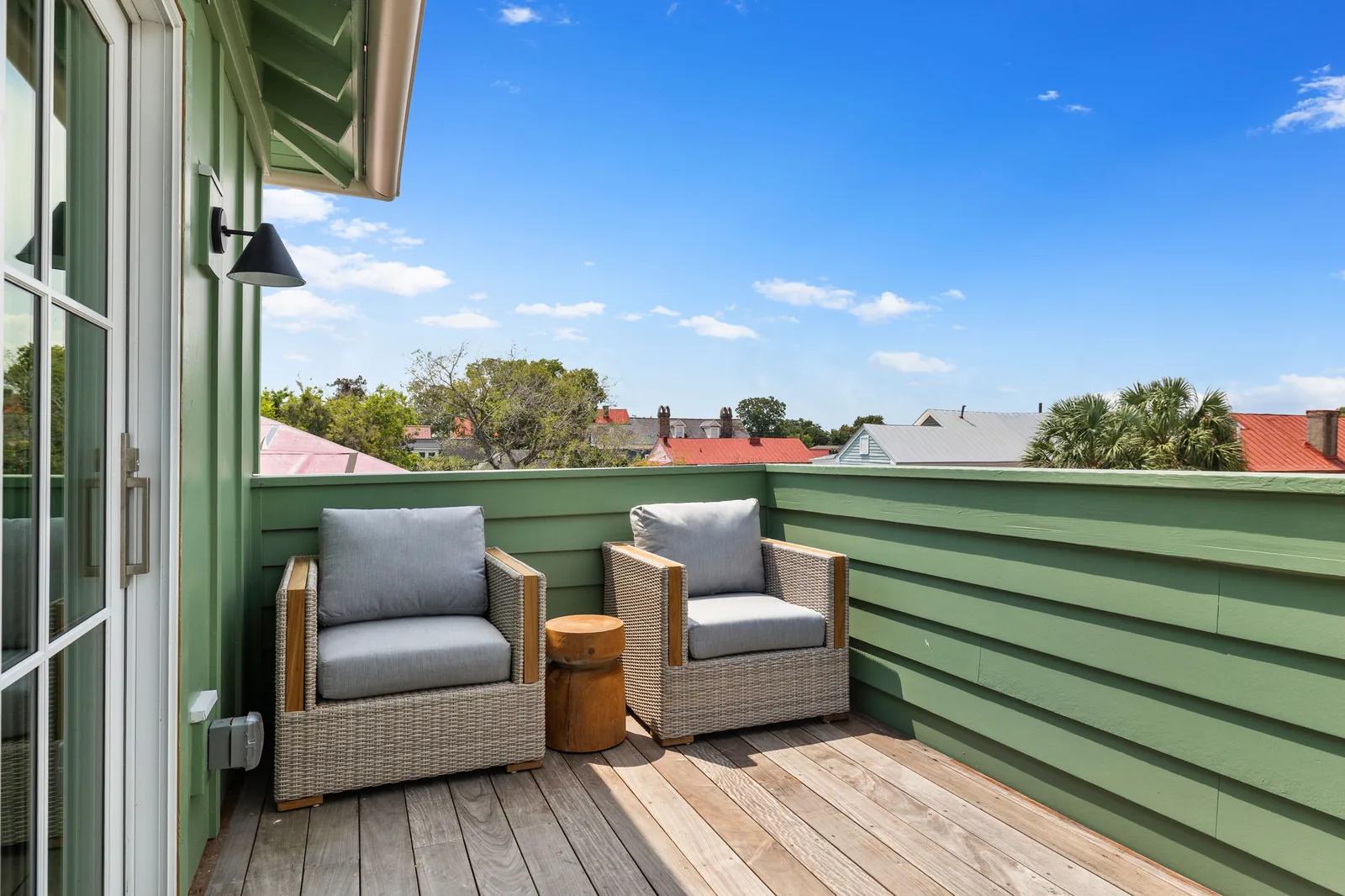 The rooftop deck overlooking the alley, with blue skies above the roofs of historic Charleston homes